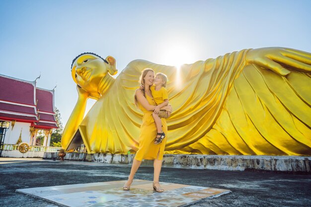 横たわっている仏像の背景に幸せな観光客の母と息子