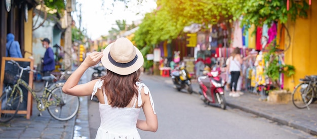 Happy traveler sightseeing at Hoi An ancient town in central Vietnam woman with dress and hat traveling landmark and popular for tourist attractions Vietnam and Southeast Asia travel concept