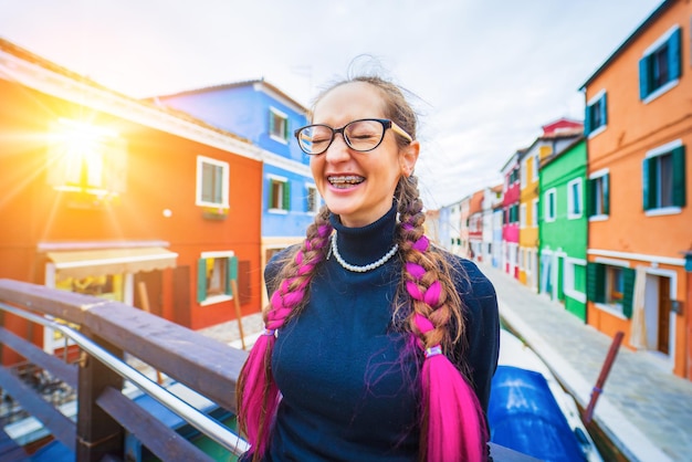 Donna felice del viaggiatore in apparecchi ortodontici divertendosi vicino a case colorate sull'isola di burano in veneziano