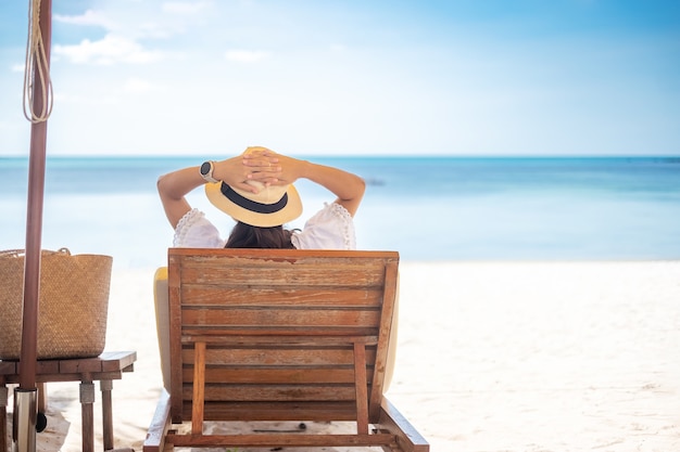 Happy traveler woman in white dress and hat enjoy beautiful sea view