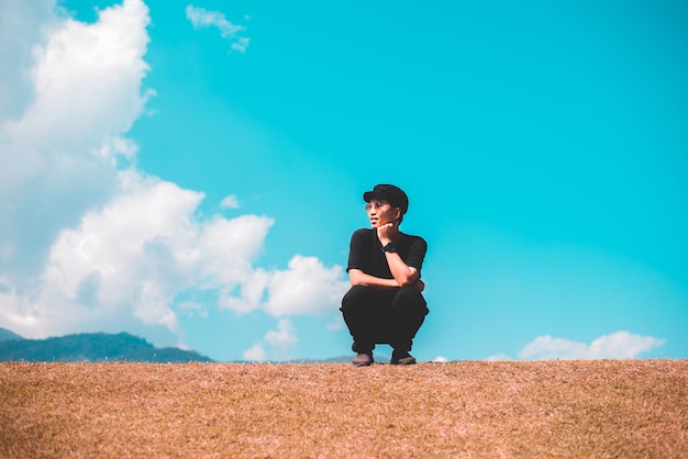 사진 맑고 푸른 하늘과 녹색 자연에 앉아 행복 여행자 아시아 남자
