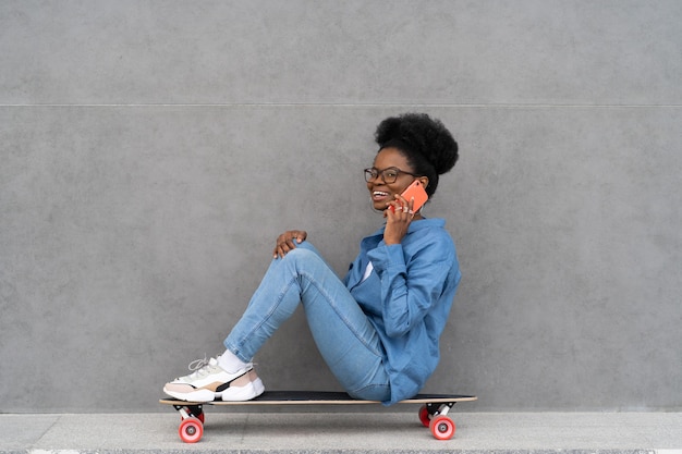 Happy trendy black girl talk on phone stylish african woman in urban denim outfit calling on cell