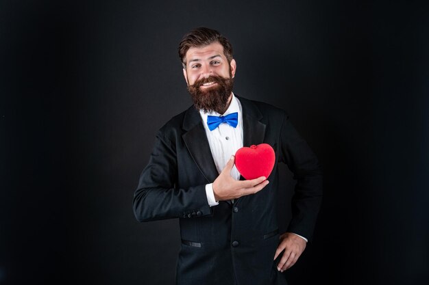 Happy tuxedo man with beard hold romantic love heart happy valentines day