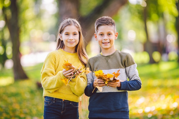 写真 幸せな双子のティーンエイジャーの男の子と女の子が秋の公園で抱き合ってポーズをとる