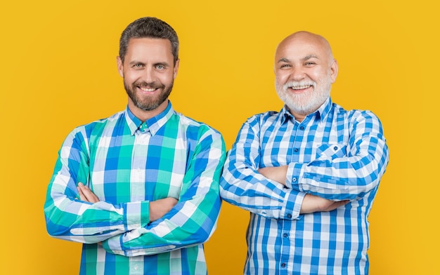 Фото Счастливые мужчины семьи двух поколений в студии двое поколений мужчин семьи на фоновом фото двух поколений мужчин семей носят клетчатую рубашку двое поколения мужчин семьи изолированы на желтом