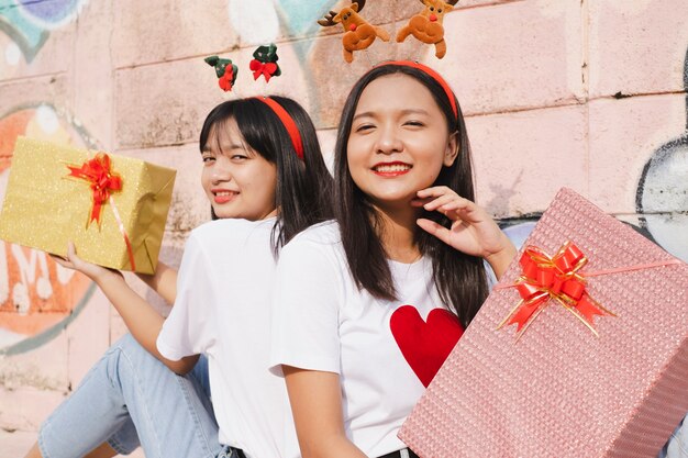 Felice due ragazze indossano il cappello di natale su sfondo colorato.