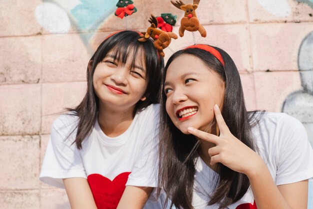 Счастливые две девушки носят рождественскую шляпу на красочном фоне.