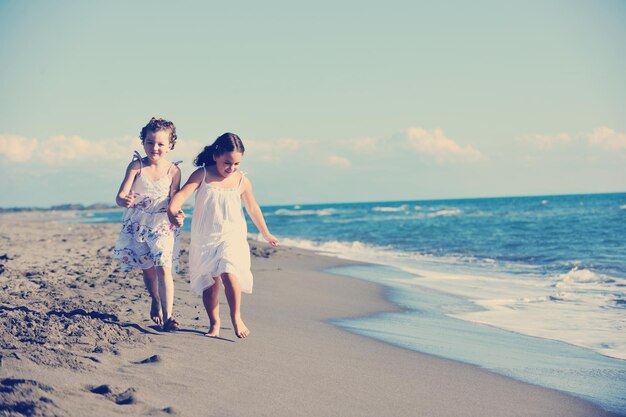 happy two little girls have fun and joy time at beautiful beach while running from joy