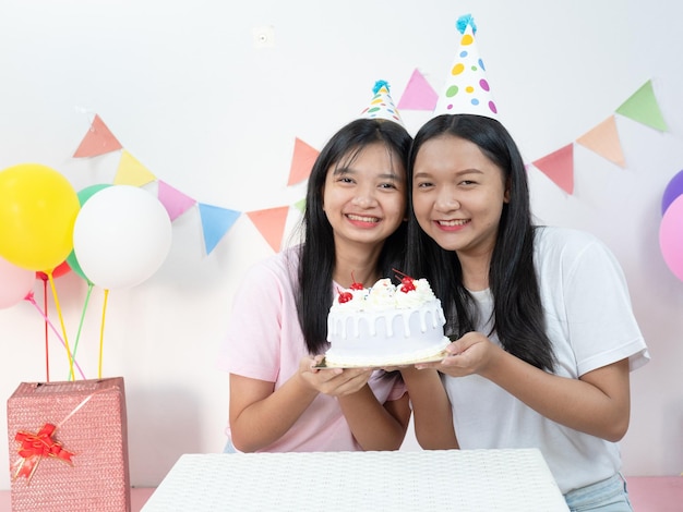 写真 2人の幸せな若い女の子が誕生日のパーティーでケーキを楽しんでいます