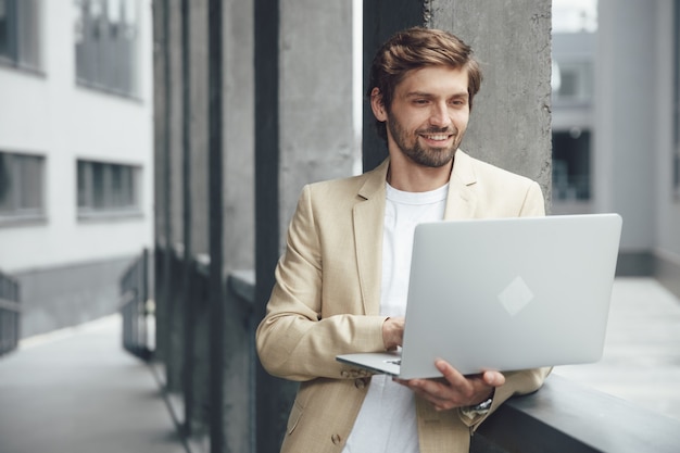 Happy unshaved man in business suit working on portable laptop on fresh air