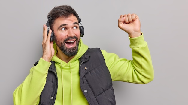 幸せな明るいひげを生やした大人の男は楽しいダンスを持っています気楽に腕を上げて音楽を聴きます