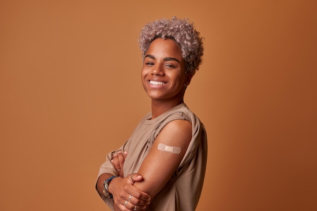 Happy vaccinated dark skinned woman showing arm with plaster bandage after covid  vaccine injection ...