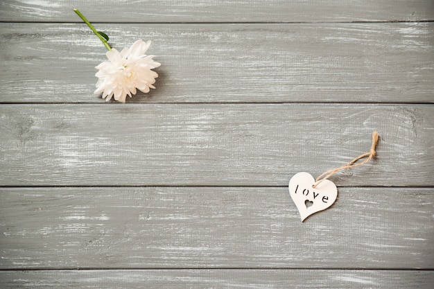 Happy Valentijnsdag achtergrond. Decoratief wit houten hart op grijze plattelander, met bloemen, het concept van Valentine.