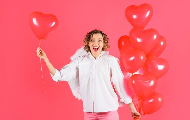 Happy valentine day curly blonde woman in angel wihgs with red heart shaped balloons female cupid