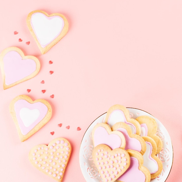 Happy Valentine's day greeting card with heart cookies, wine glasses and wine on pastel pink background.