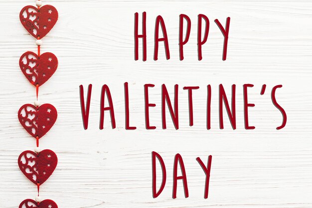 Photo happy valentine's day text sign happy valentines concept red hearts decorations on white rustic wooden background with space for text greeting card