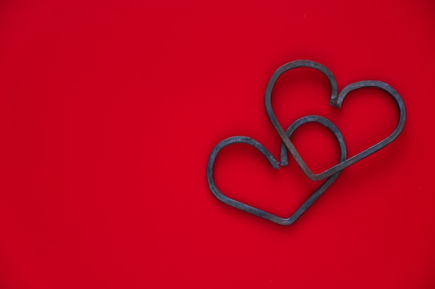 Happy Valentine's day. Two forged metal hearts on red background. Flat lay, copy space.