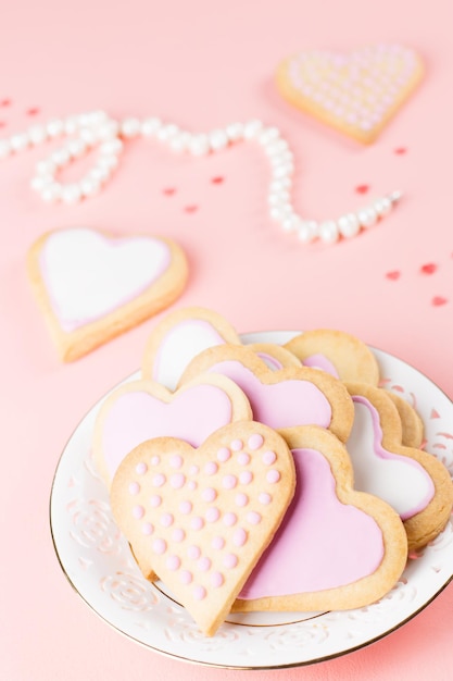 Happy Valentine's day wenskaart met hart cookies, wijnglazen en wijn op pastel roze achtergrond.