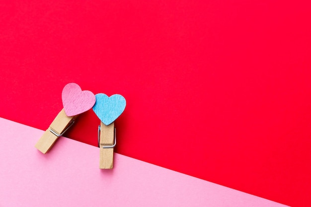 Happy valentines day 2021. Two clothespin with hearts pinned to a pink sheet of paper. Postcard