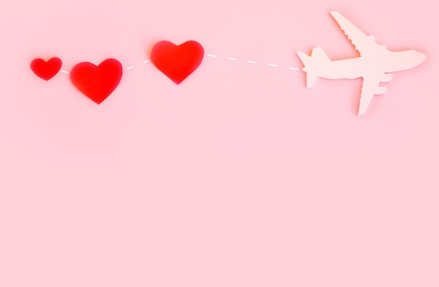 幸せなバレンタインデー。赤いハートとピンクの背景の子供用飛行機