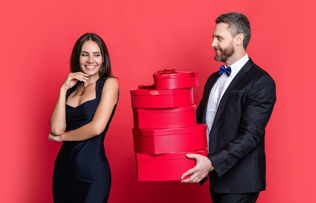 Happy Valentines day Couple in love isolated on red Birthday couple with gift Loving man giving present gift box for Valentines day to surprised woman Man receiving present Family anniversary