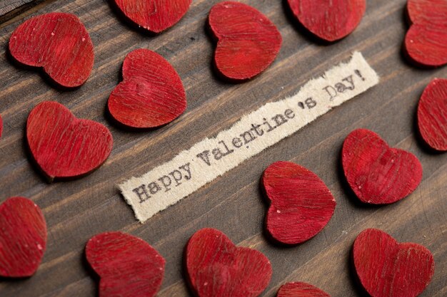 Happy Valentines day getypte tekst Valentines Day groeten concept Kleine rode houten harten close-up Valentines wenskaart op houten achtergrond