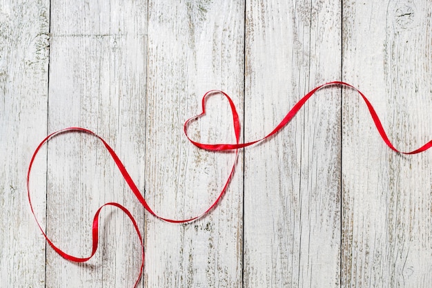 Happy Valentines Day. Red Ribbon Heart on white wooden.