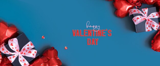 Happy Valentines Day text with gift box and red heart shape baloons on blue background Valentines Day greeting card