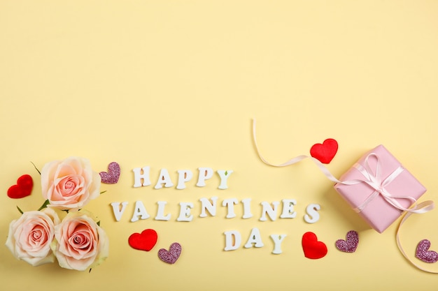 Happy Valentines day text with pink roses and hearts on yellow background