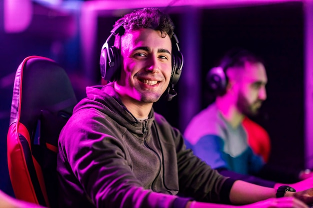 a happy video game champion playing video game at gaming room and smiling at the camera
