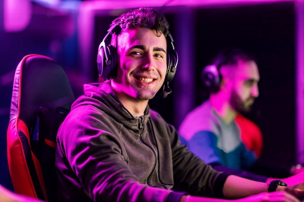 A happy video game champion playing video game at gaming room and smiling at the camera