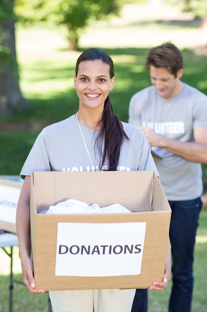 Photo happy volunteer brunette holding donation box