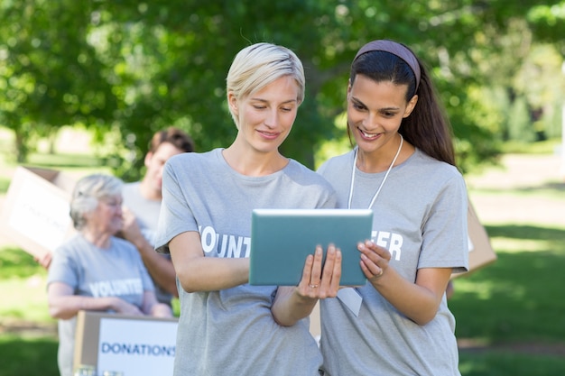 Happy volunteer friends using tablet pc 