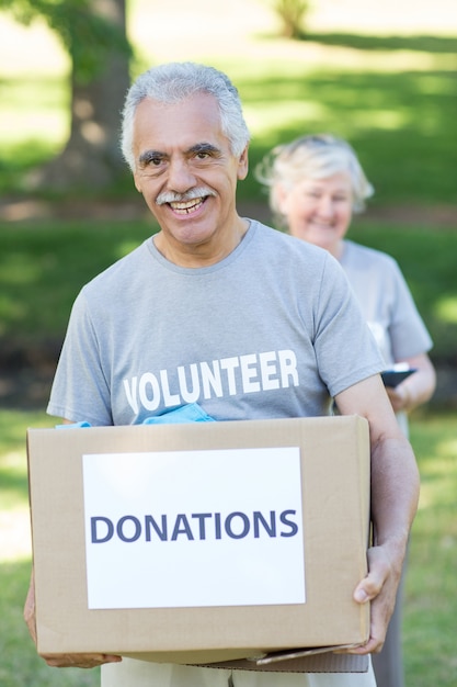 Photo happy volunteer senior holding donation box