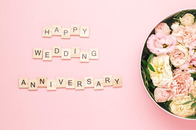 Photo happy wedding anniversary lettering on the wooden squares with letters on the pink background and