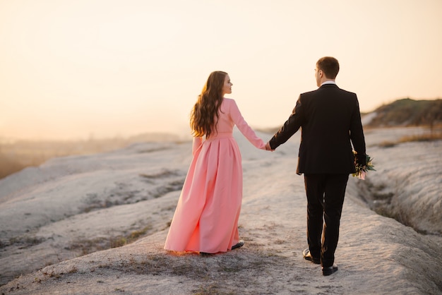 Happy wedding couple admire the beautiful landscape at sunset. Wedding concept.