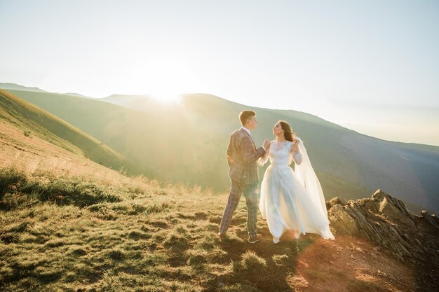 幸せな結婚式のカップルは山を歩いています