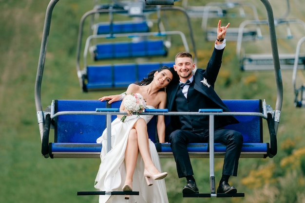 Happy wedding couple riding cableway from mountain.