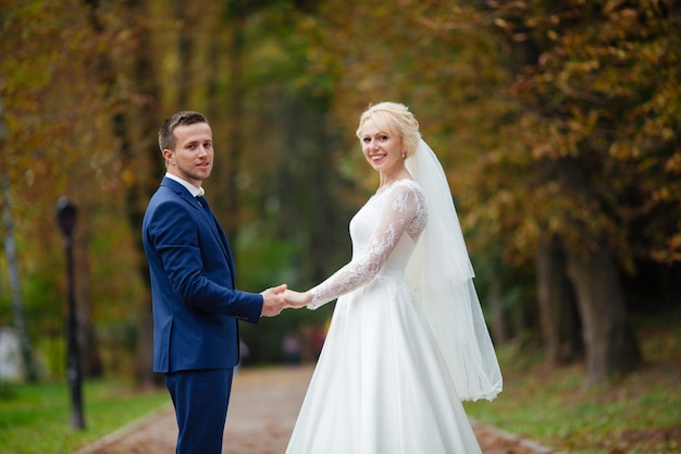 公園を歩いて幸せな結婚式のカップル