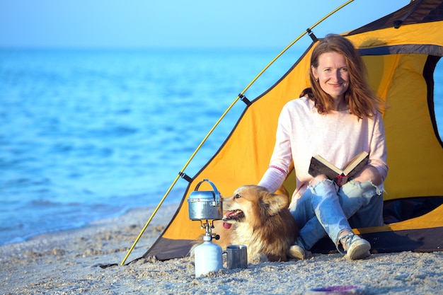 Happy weekend by the sea - girl with a dog in a tent on the beach at dawn. Ukrainian landscape at the Sea of Azov, Ukraine