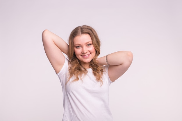 Happy white blonde woman with curly hair in white tshirt raising her hands in hair