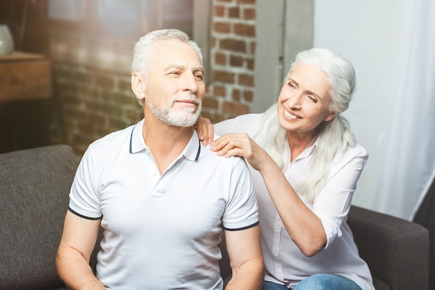 Happy wife making shoulder massage for husband in living room