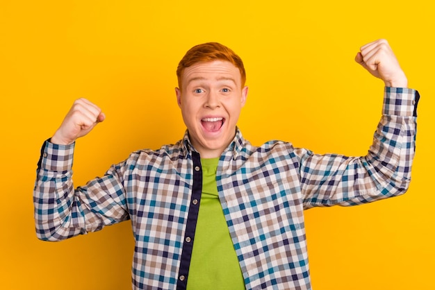 Photo happy winner young handsome man gesturing keeping mouth open while standing against yellow background