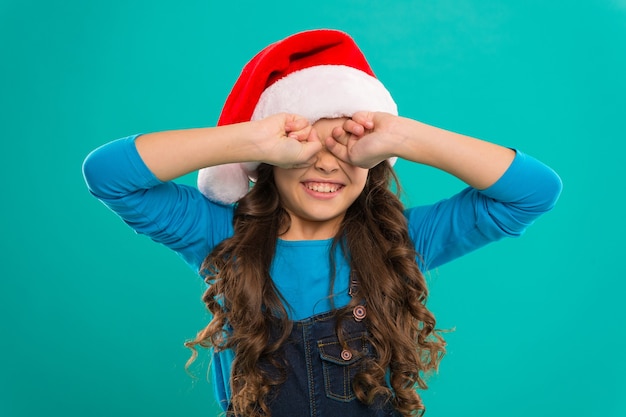 幸せな冬の休日。小さい女の子。クリスマスにプレゼント。子供時代。新年会。サンタクロースの子供。クリスマスショッピング。サンタの帽子をかぶった小さな女の子の子供。クリスマスはここにあります。幸せな瞬間をとらえます。