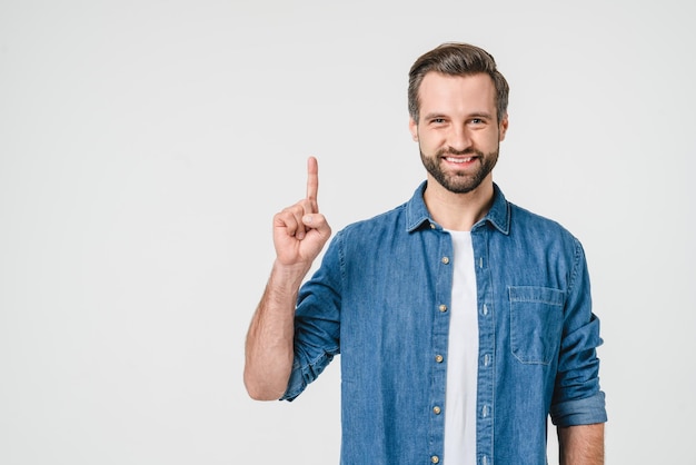 Foto felice con un sorriso dentato giovane uomo caucasico studente freelance con l'idea di puntare verso l'alto con il dito su copyspace isolato sullo sfondo bianco