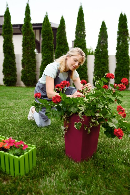 Happy woman in apron works with flowers in the garden