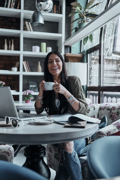 Photo happy woman. attractive young smiling woman holding a cup of coffee and looking away