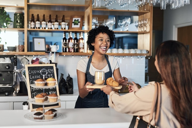 Foto barista donna felice e serve il cliente al bar per il pagamento del servizio o l'ordine al bancone della caffetteria cameriera africana o dipendente in un ristorante per piccole imprese che aiuta il cliente alla cassa