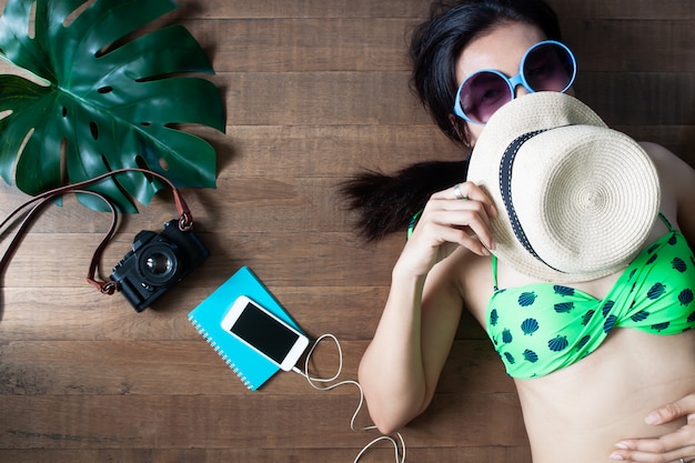 Happy woman in bikini lying down on wooden background