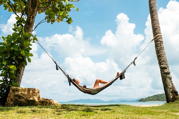 Happy woman in black bikini relaxing in hammock